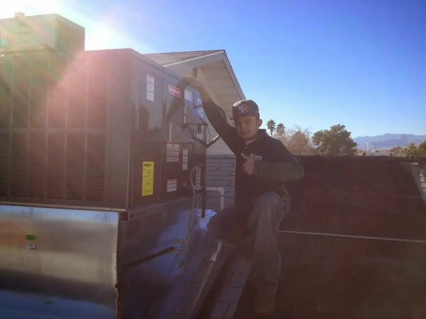 HVAC technician performing AC Tune-Up on a rooftop unit in Weatherford